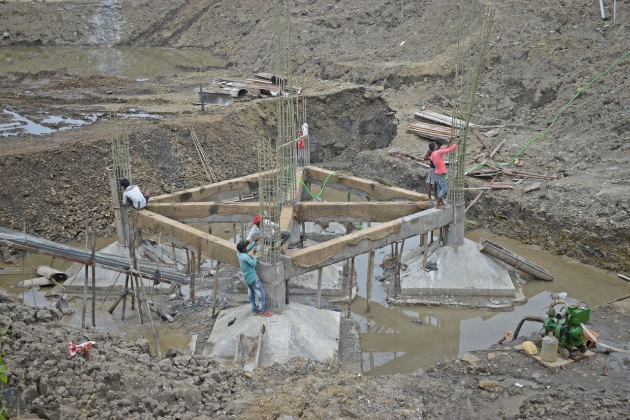 Cimientos que Salvan Vidas: Por qué el Estudio de Suelos es el ADN de tu Proyecto Workers constructing a building foundation with rebar and wooden supports outdoors.