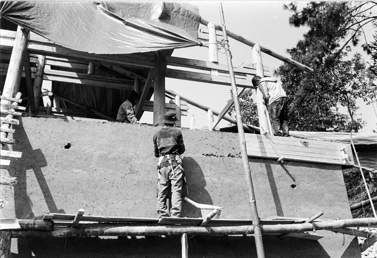 La Construcción del Futuro: Cómo la IA y BIM están transformando la eficiencia en la obra Monochrome image of workers at a construction site with scaffolding.
